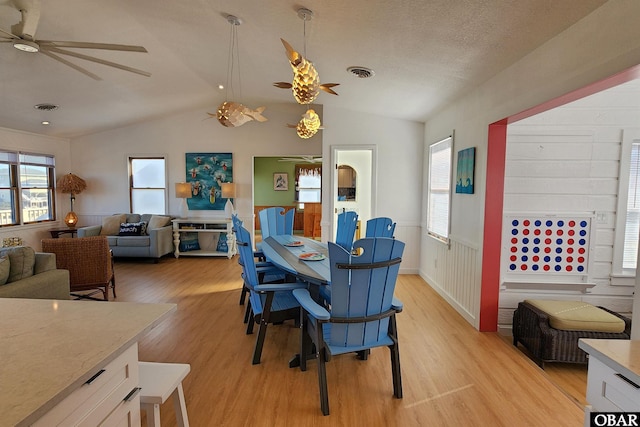 dining room with light wood-type flooring, visible vents, and vaulted ceiling