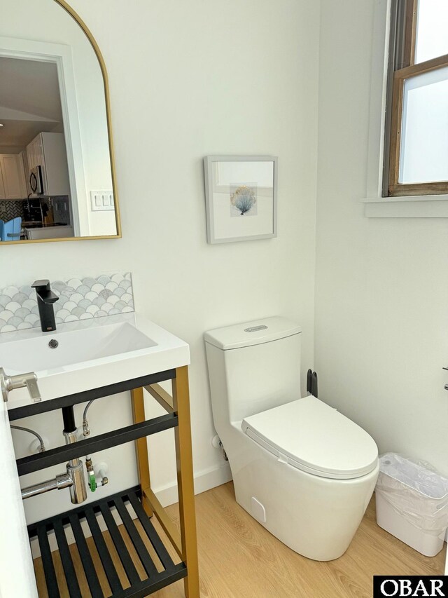 half bathroom featuring a sink, toilet, and wood finished floors