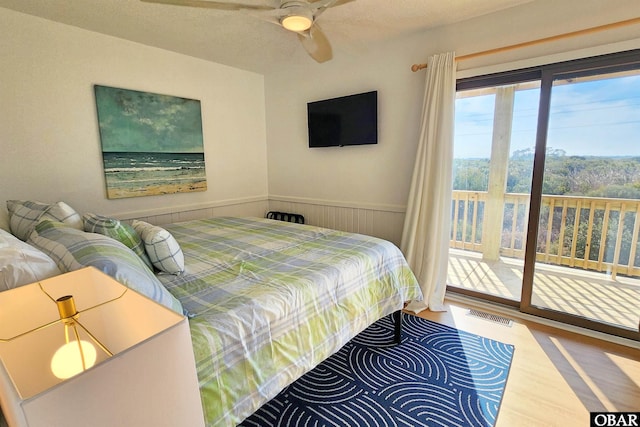 bedroom featuring wainscoting, wood finished floors, visible vents, and access to exterior