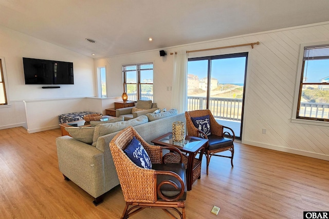 living room featuring light wood-type flooring, plenty of natural light, and vaulted ceiling