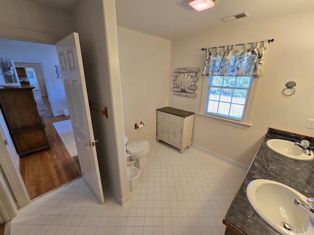 bathroom with toilet, double vanity, a sink, and visible vents