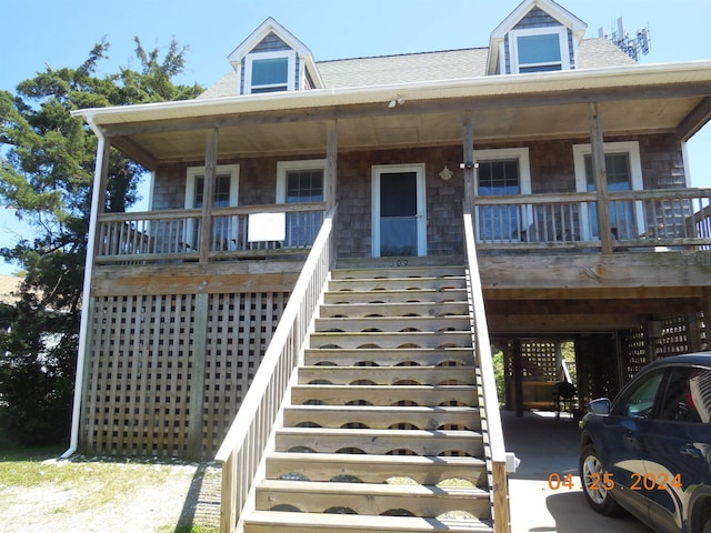 view of front facade with stairway, covered porch, and a shingled roof