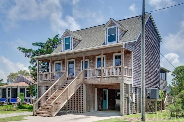 coastal home featuring covered porch, a shingled roof, a carport, cooling unit, and concrete driveway