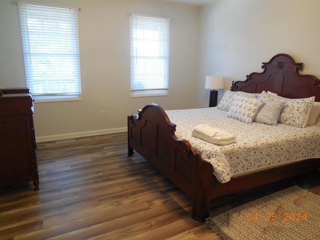 bedroom featuring wood finished floors, baseboards, and multiple windows
