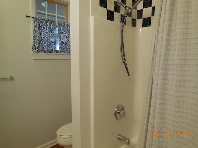 bathroom with shower / bath combo with shower curtain, toilet, and baseboards