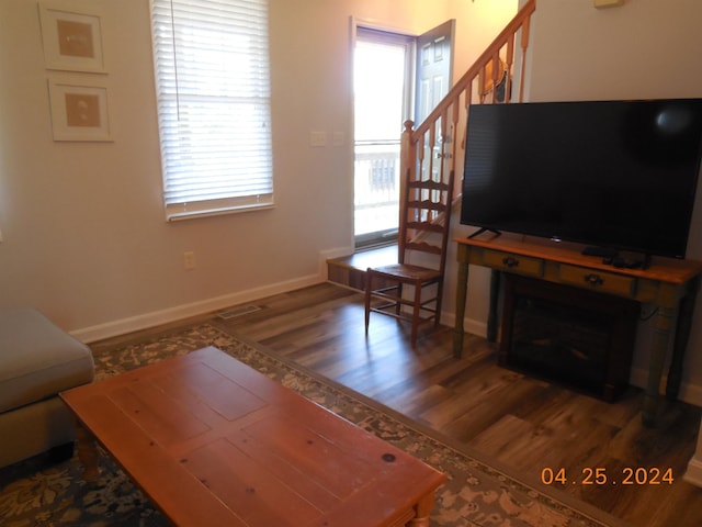 living room featuring baseboards, stairway, and wood finished floors