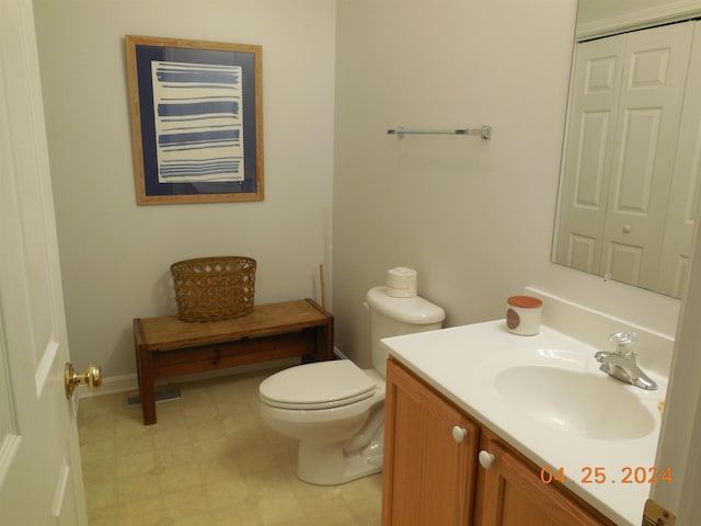 half bath with toilet, tile patterned floors, and vanity
