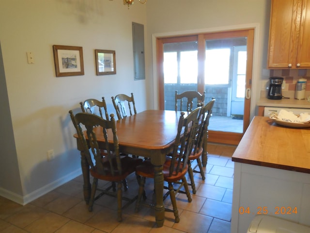 dining room featuring light tile patterned floors, electric panel, and baseboards
