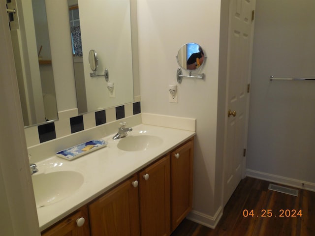 bathroom featuring double vanity, wood finished floors, visible vents, and a sink