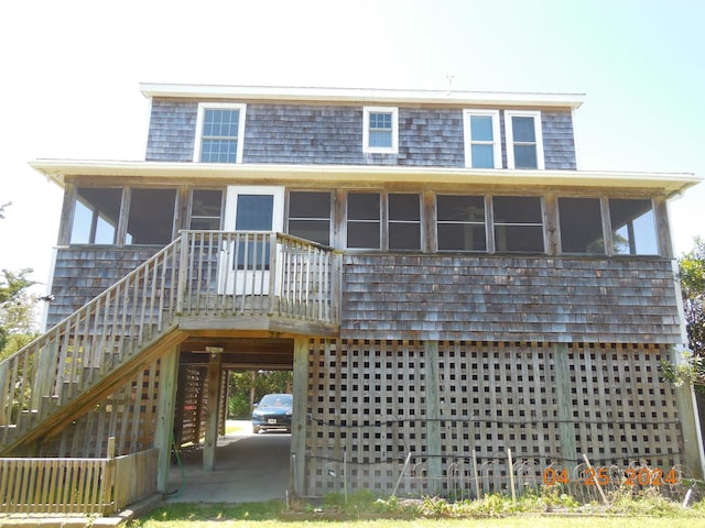 rear view of property featuring a carport, a sunroom, and stairs