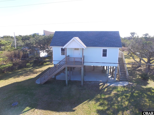 view of front of property featuring a shingled roof, driveway, a front lawn, and stairs