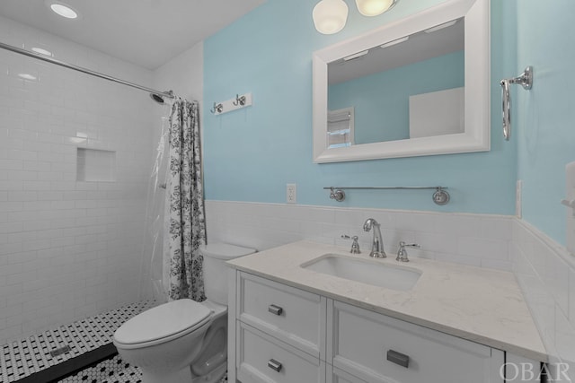 full bath with a stall shower, tile walls, vanity, and toilet