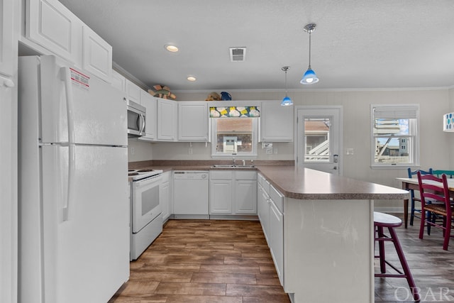 kitchen featuring a peninsula, white appliances, white cabinetry, a kitchen breakfast bar, and hanging light fixtures