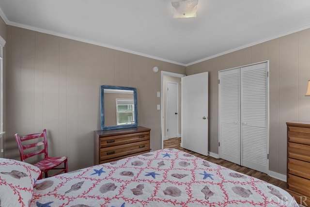 bedroom featuring baseboards, a closet, wood finished floors, and crown molding