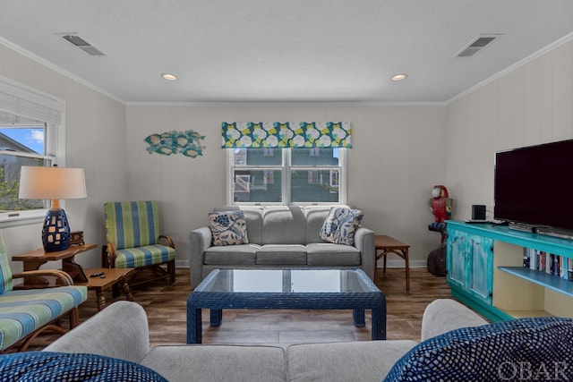 living area with ornamental molding, visible vents, baseboards, and wood finished floors