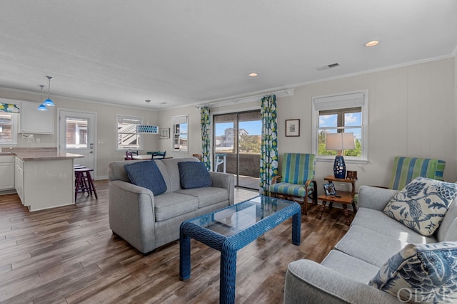 living room with recessed lighting, visible vents, crown molding, and wood finished floors