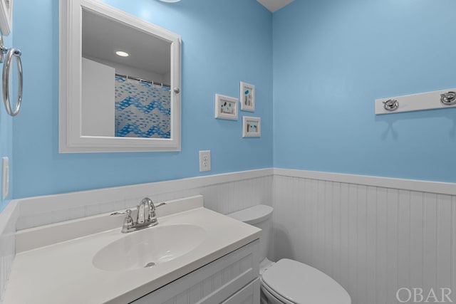 full bath featuring wainscoting, vanity, and toilet