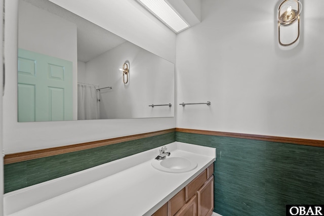 bathroom with a shower with shower curtain, vanity, and wainscoting