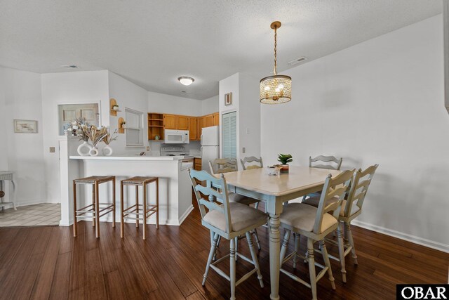 dining area with dark wood-style floors, baseboards, a textured ceiling, and ceiling fan with notable chandelier