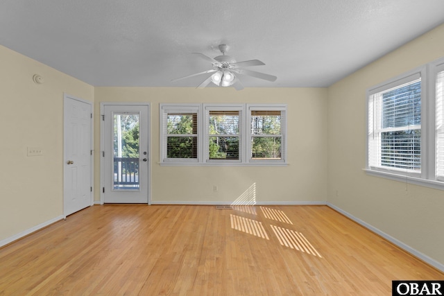 spare room with baseboards, ceiling fan, and light wood finished floors