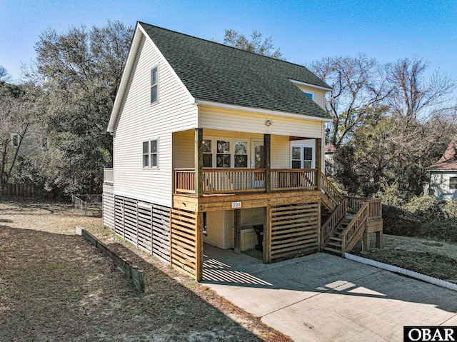 view of front facade featuring concrete driveway, a porch, roof with shingles, and stairway