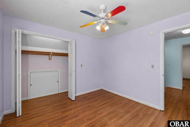 unfurnished bedroom featuring ceiling fan, a closet, baseboards, and wood finished floors