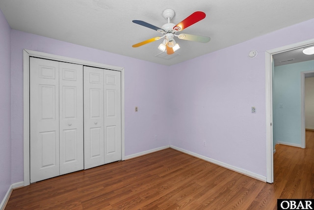 unfurnished bedroom featuring ceiling fan, a closet, baseboards, and dark wood-type flooring