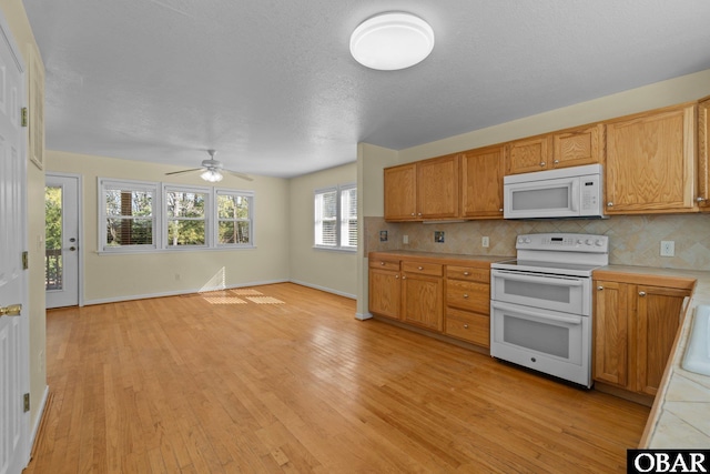 kitchen with white appliances, backsplash, light wood-style flooring, and baseboards