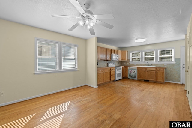 kitchen with white appliances, baseboards, brown cabinets, light countertops, and light wood-type flooring