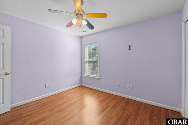 empty room featuring light wood finished floors, a ceiling fan, visible vents, and baseboards