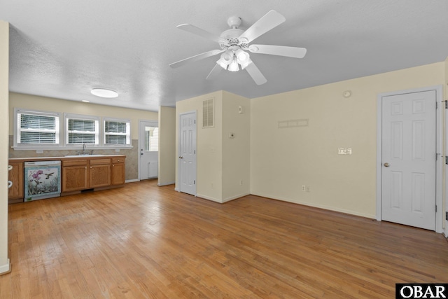 kitchen featuring baseboards, visible vents, brown cabinetry, a textured ceiling, and light wood-style floors