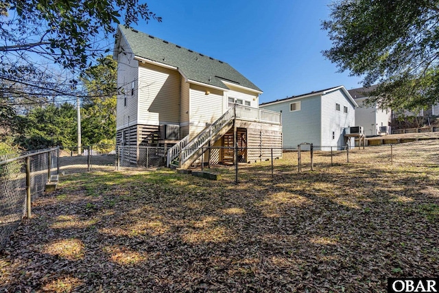 back of house with a fenced backyard, stairway, a deck, and roof with shingles