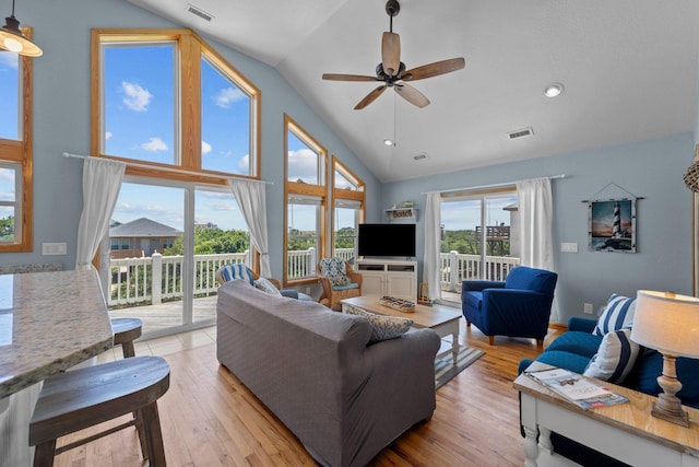 living area with high vaulted ceiling, light wood-type flooring, visible vents, and a ceiling fan