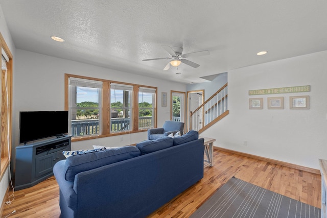 living room featuring recessed lighting, stairway, light wood-style flooring, a textured ceiling, and baseboards