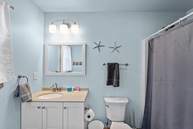 full bathroom with toilet, a textured wall, and vanity