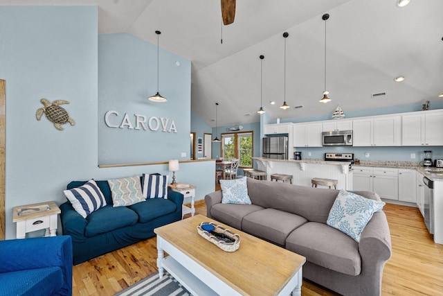 living area featuring high vaulted ceiling, light wood-type flooring, and a ceiling fan