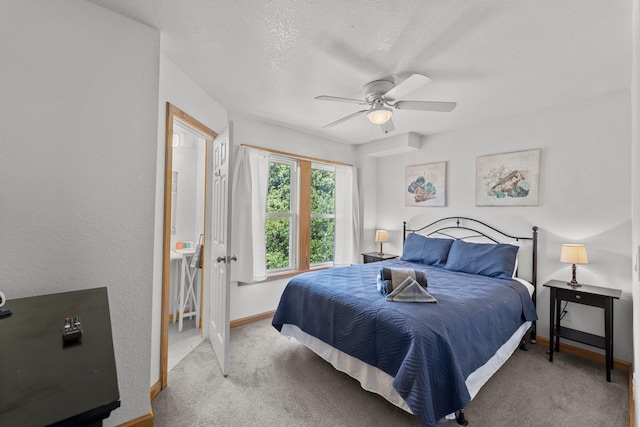 bedroom featuring baseboards, a textured ceiling, a ceiling fan, and light colored carpet