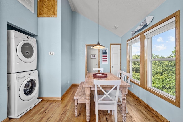 laundry room with a textured ceiling, laundry area, baseboards, light wood-style floors, and stacked washer / drying machine