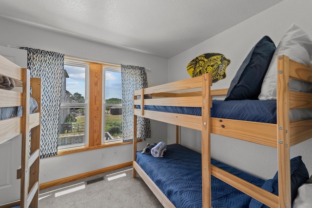 carpeted bedroom with baseboards, visible vents, and a textured ceiling