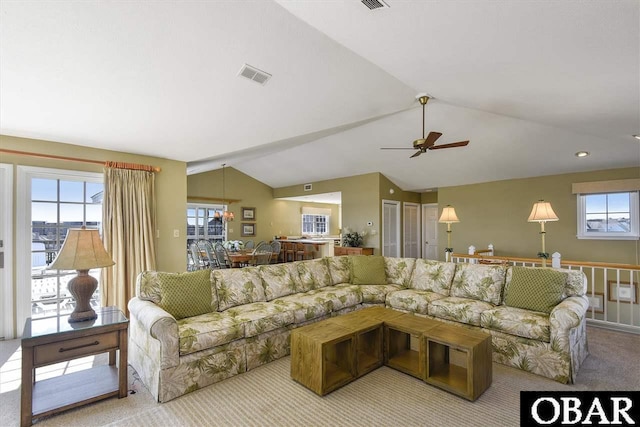 living area featuring light carpet, vaulted ceiling, visible vents, and a ceiling fan