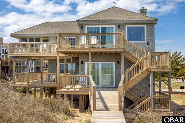 rear view of property featuring a shingled roof, stairway, a chimney, and a wooden deck