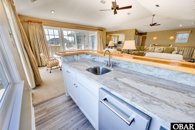 kitchen with a sink, white cabinetry, open floor plan, dishwasher, and plenty of natural light