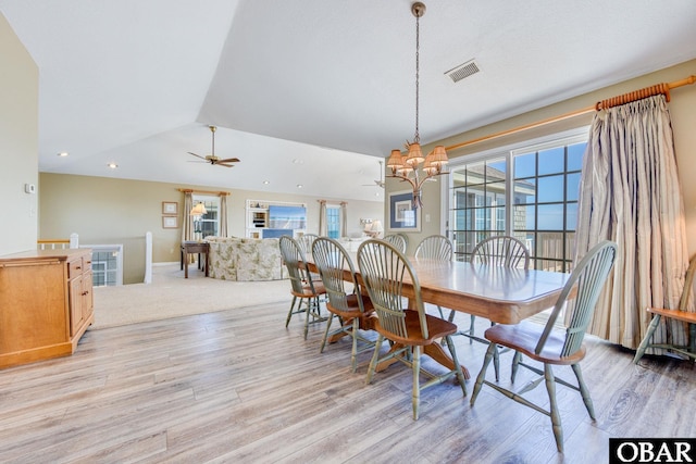 dining room featuring lofted ceiling, visible vents, light wood-type flooring, baseboards, and ceiling fan with notable chandelier