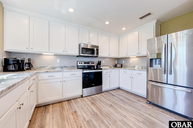 kitchen featuring light wood finished floors, visible vents, backsplash, appliances with stainless steel finishes, and white cabinets