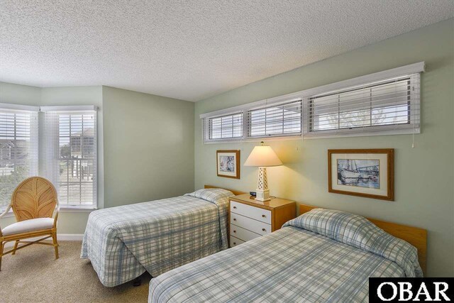 bedroom featuring baseboards, a textured ceiling, and light colored carpet