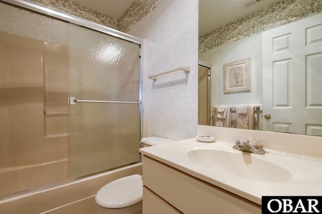 bathroom with toilet, bath / shower combo with glass door, vanity, and wallpapered walls