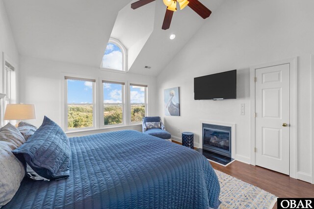 bedroom with baseboards, dark wood finished floors, a ceiling fan, a glass covered fireplace, and recessed lighting