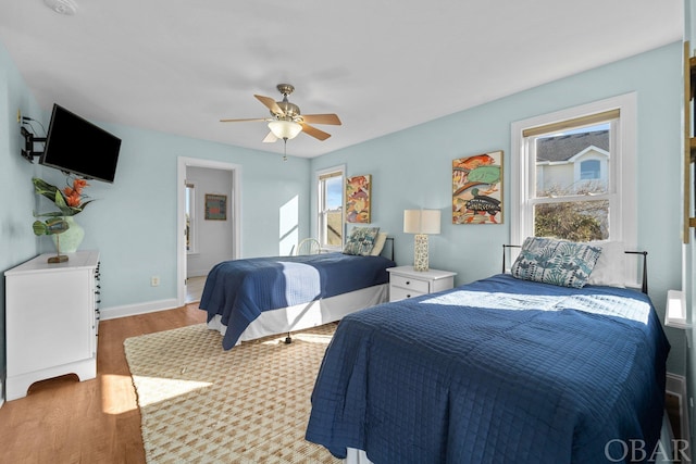 bedroom with light wood-style floors, ceiling fan, and baseboards