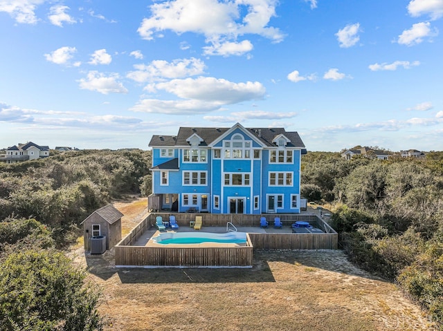 rear view of house with a fenced in pool, an outbuilding, a storage unit, central AC unit, and a fenced backyard