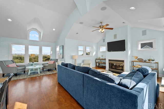 living room with a wealth of natural light, a glass covered fireplace, dark wood-style flooring, and visible vents